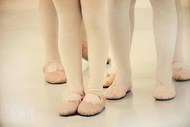 IMG_0024 Close-up van kindervoeten in roze balletschoentjes en roze maillots op de studiovloer